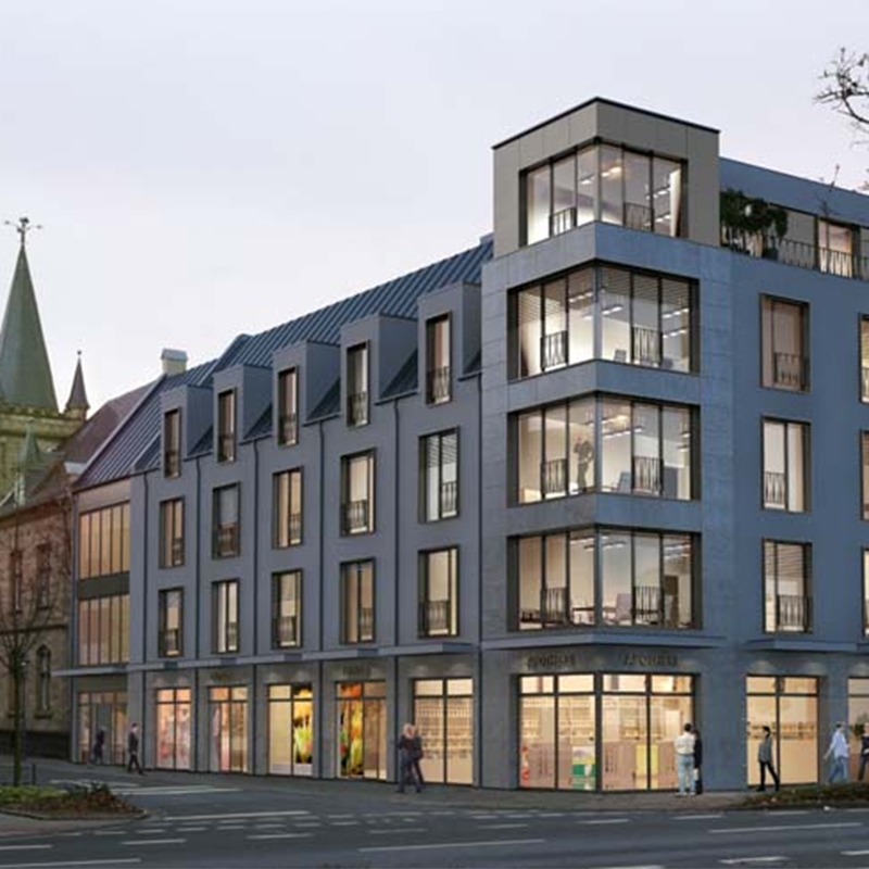 Außenansicht der Praxis von dmt. Physiotherapie. Modernes Gebäude mit heller Fensterfront und 3 Stockwerken. Im Hintergrund ist eine Kirche zu sehen.