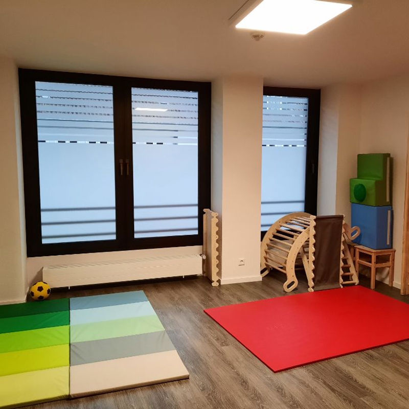Übungsraum der dmt. Physiotherapie Praxis mit Übungsgeräten, farbigen Matten und einem Trainingsball.