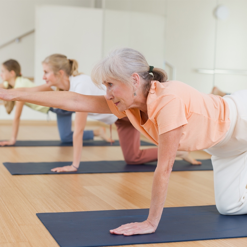 Präventionskurs Wirbelsäule und Pilates nach §20 SGB V. Drei Frauen in verschiedenen Altersgruppen auf einer Matte trainieren.