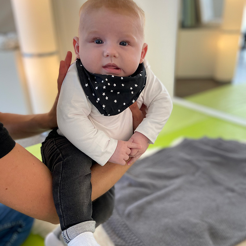 dmt. Kids. Physiotherapeutin führt Übung bei einem Baby durch.