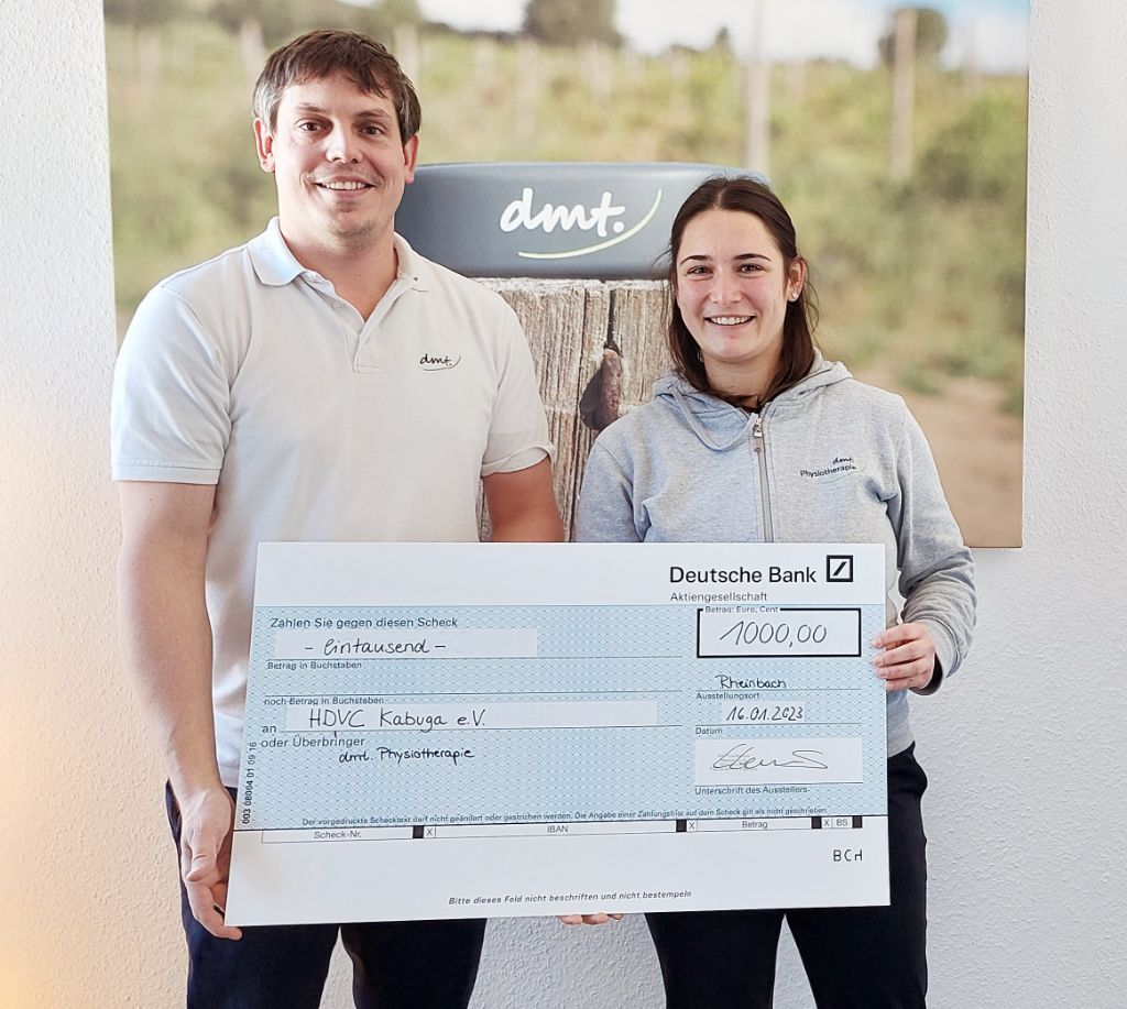 Links steht Dennis und rechts Anne. Beide halten einen Spendencheck in den Händen.