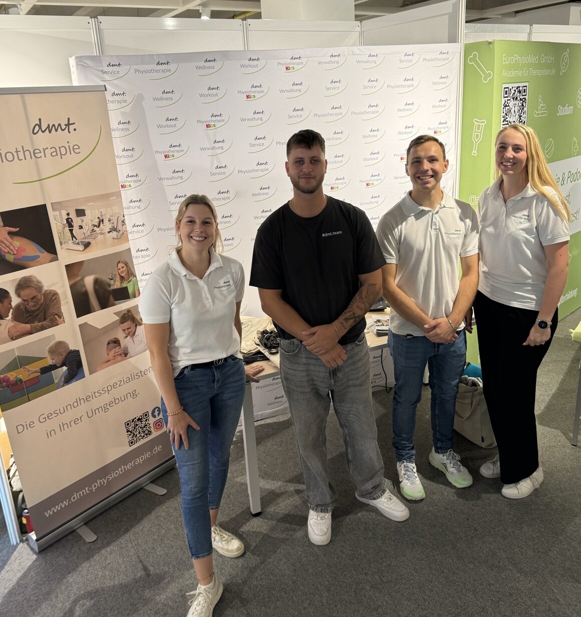 Vier Mitarbeiter der dmt. Physiotherapie stehen vor Ihrem Stand bei der Rheinbacher Ausbildungsmesse.
