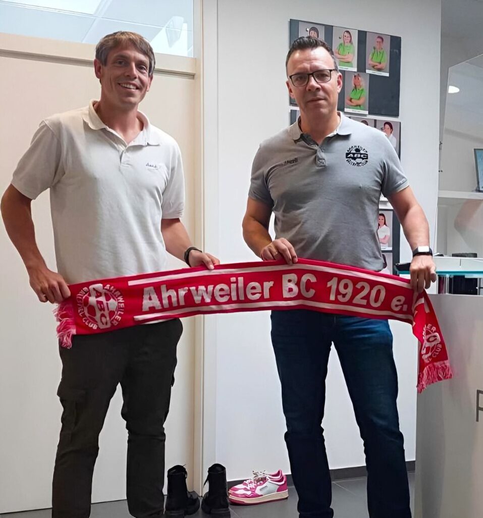 Dennis hält mit einem Vertreter des Ahrweiler BCs einen Fanschal in der Hand.