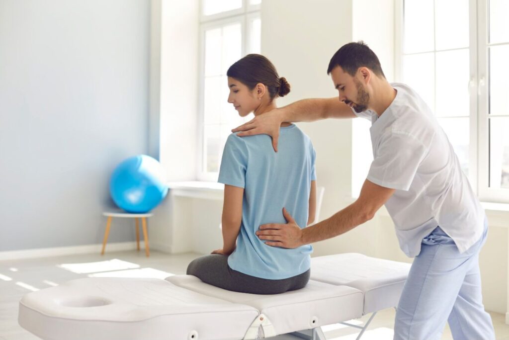 Skoliosetherapie nach Schroth. Physiotherapeut behandelt den Rücken einer Frau.