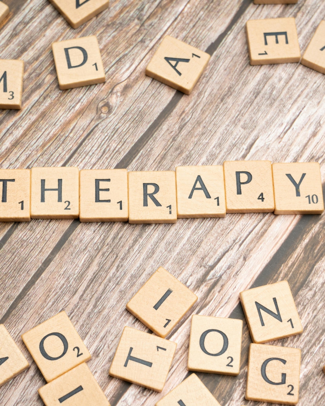Das Bild zeigt Holzplättchen mit Buchstaben. Die Buchstaben ergeben das Wort "Therapie".