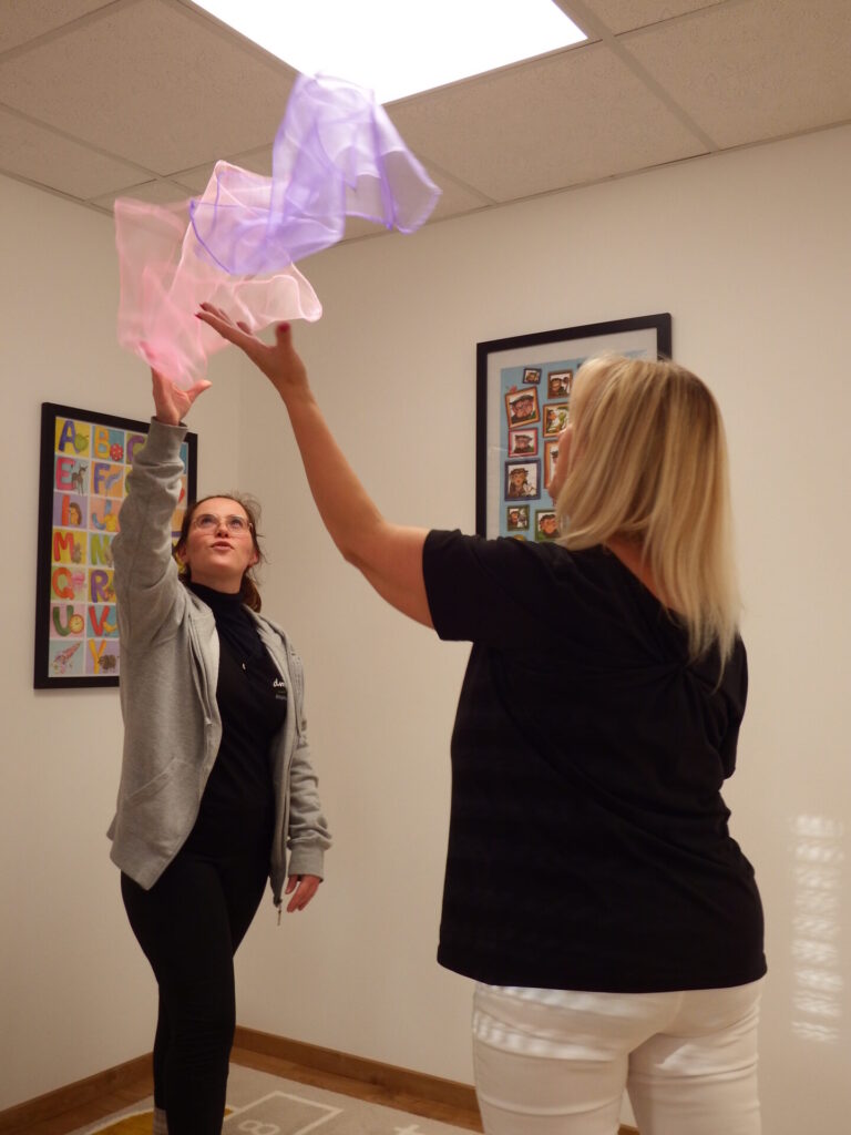 Die Patientin und Jessie werfen Schwingtücher nach oben.