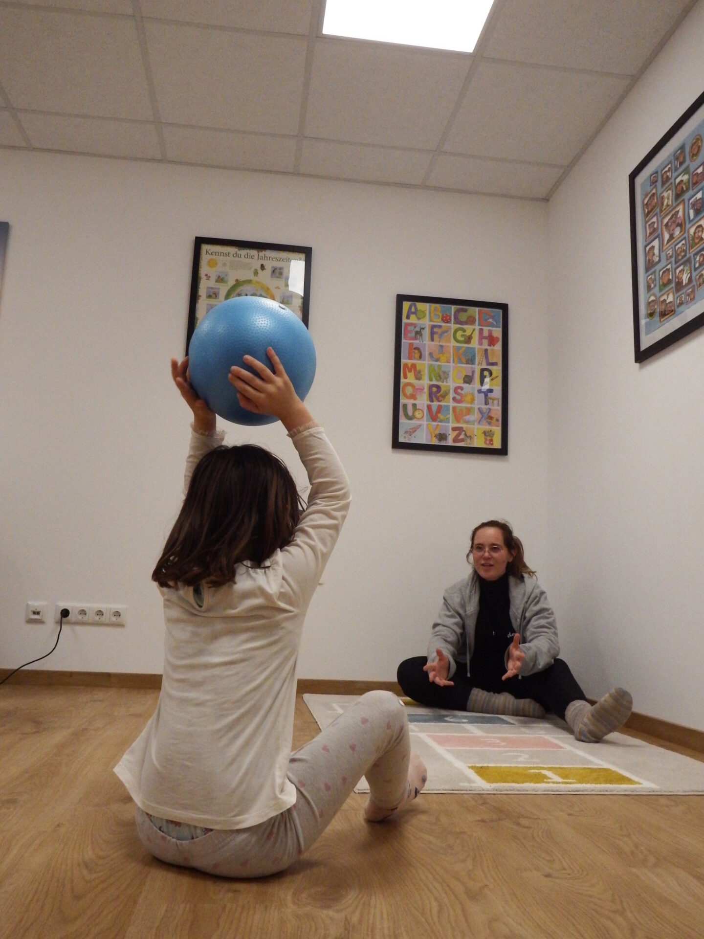 Jessi übt beim hin-und herrollen eines Balles mit ihrer Patienten das Sprechen.