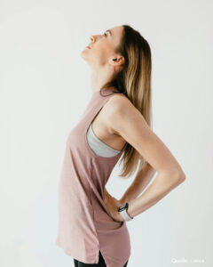 Frau stützt die Hände in den Rücken und streckt sich.