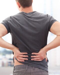 Foto zeigt Mann, der sich mit beiden Händen an den Rücken greift.
