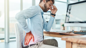 Bild zeigt einen Mann bei der Arbeit, der sich an den schmerzenden Rücken fasst.