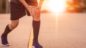 Bild zeigt Jogger der sich ans linke Knie greift
