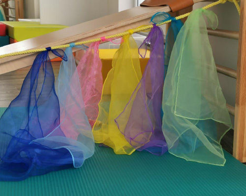 Psychomotorik Übung zu Psychomotorik. 6 durchsichtige bunte Tücher an einem Seil aufgehangen.